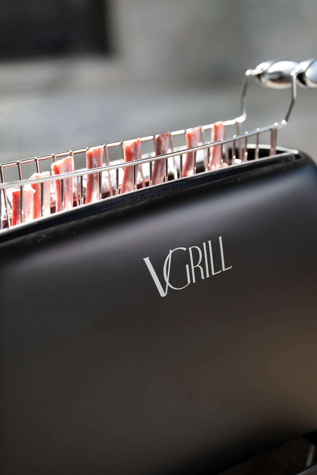 Close-up of pork chops positioned vertically inside the black VGrill vertical grill